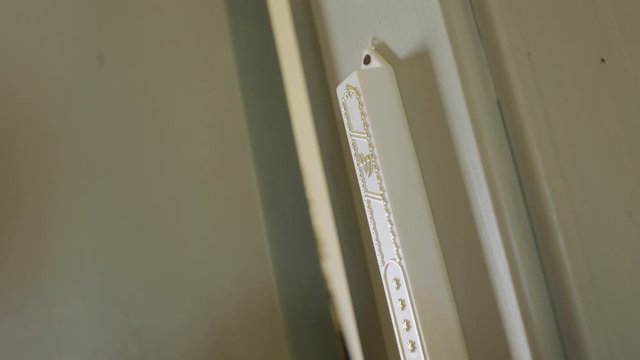 Hand touches a Jewish Mezuzah located in entrance of a room
