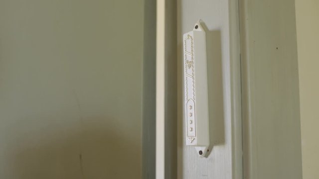 Mezuzah on the entrance of a room is touched by a man's hand