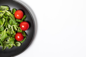 Fresh green salad with tomatoes on a white background, flat lay