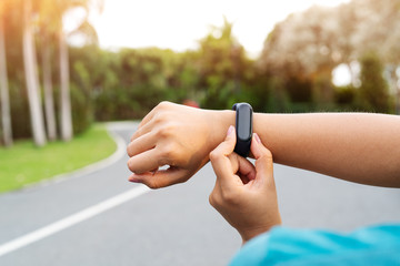 fitness woman runner setting up smart watch before running. Outdoor exercise activities