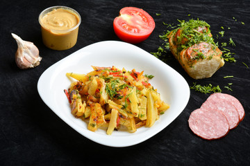 Fried potatoes with spices on a dark background, greasy food