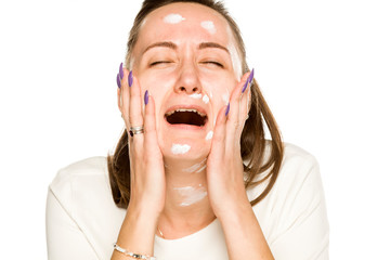 Crying woman applying face cream on white background