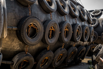 A huge Marine Pneumatic heavy rubber fender surrounded by tires fixed with chains.