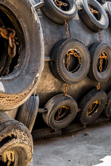 A huge Marine Pneumatic heavy rubber fender surrounded by tires fixed with chains.