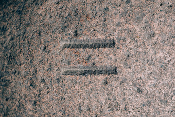 An equal sign carved on the stone. Mathematical sign on granite. Stone engraving