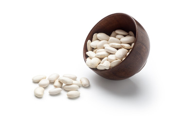 White kidney beans dumped from a wooden bowl. Isolated on white background.