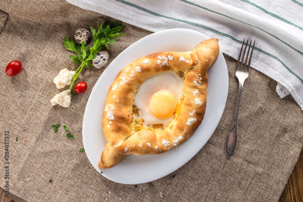 Wall mural Adjarian Khachapuri traditional Georgian dish with sulguni cheese filled bread and egg yolk on tablecloth