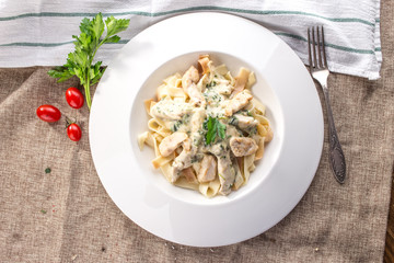 fettuccine pasta with chicken and cheese sauce on white plate on tablecloth