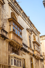 street with traditional balconies and old buildings in historical city Valletta Malta