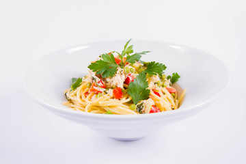 Spaghetti with cream sauce with smoked mackerel, peas ,bell pepper and some parsley on a white plate on a white background