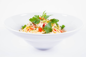 Spaghetti with cream sauce with smoked mackerel, peas ,bell pepper and some parsley on a white plate on a white background