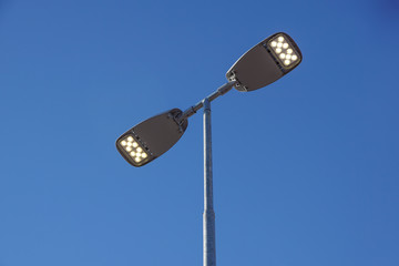 Three LED Street Lamps Affixed to an Iron Post Against a Deep Blue Sky