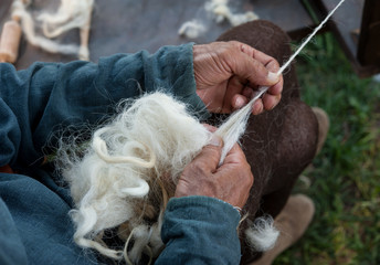 Craftsman using an old spinning wheel to turn wool into yarn.