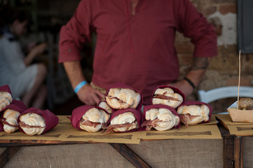 Street food ready to serve on a food stall. Italian cured ham burgers in the foreground.