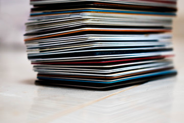 A large stack of different colored credit cards on a white tile floor with a blurred background.