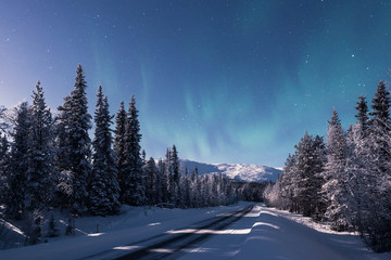A road leading towards snow covered Pallas fell at winter night in Pallas-Yllästunturi national...