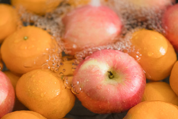 Hands washing fresh orange and apple.