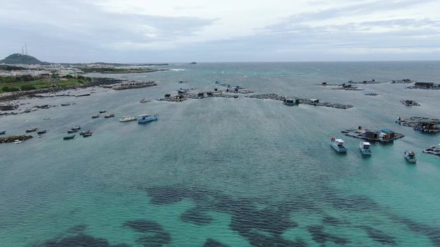 At one exotic island in Vietnam, flying over fishing boats and tranquil floating houses with sea corals underneath crystal clear blue water. Phan Thiet, Vietnam.