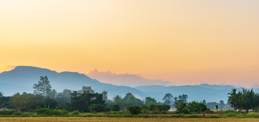 Landscape scene of colorfull sunset sky in northern Thailand with mountain range , rice field and forest.