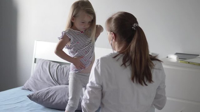 Doctor listens to a little girl in a hospital with a stethoscope.