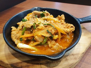 Spicy roast pork with onions sliced on wooden cutting board in Korean restaurant (Jeyuk Bogeum)