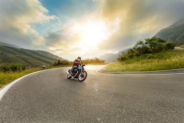 Motorcycle driver riding in Alpine landscape