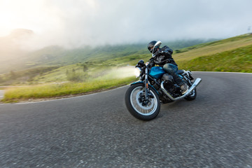 Obraz na płótnie Canvas Motorcycle driver riding in Alpine landscape.