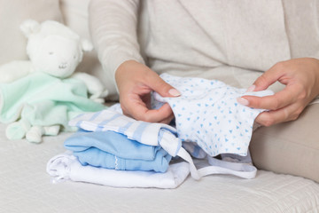 A pregnant woman sitting on a sofa preparing things for the birth of a child.