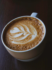 Cup of cappuccino with latte art wooden background.