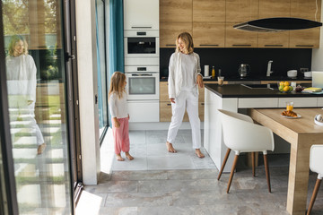 Mother and daughter entering the kitchen stock photo