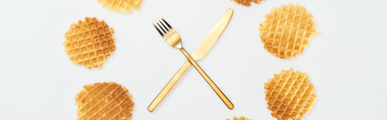 panoramic shot of waffles with fork and knife in middle isolated on white