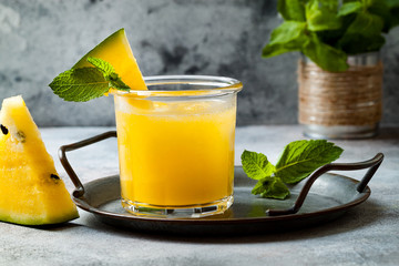 Glass of fresh golden watermelon juice or smoothie with slices of watermelon. Refreshing cold summer fruit drink