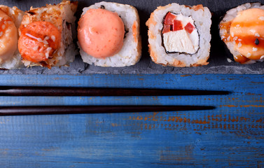 Sushi rolls assortment served on slate plate on blue table