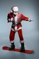 Senior Santa Claus holding sack, standing on snowboard