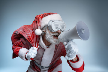 Mature Santa Claus with sack speaking at megaphone