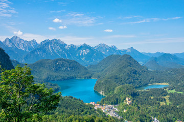 Naklejka na ściany i meble Beautiful summer day in bavarian Alps with a view to Alpsee lake and Neuschwanstein castle Germany from hiking trail 