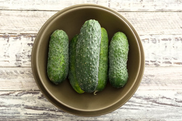  Top view fresh farm cucumbers in rustic plates on wooden barn board table with broun towel. 