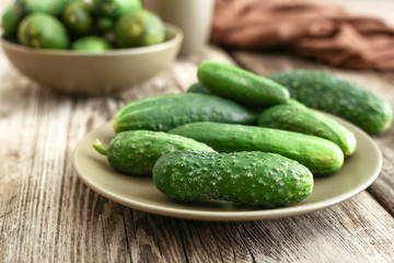 Fresh farm cucumbers in rustic plates on wooden barn board table with broun towel. 