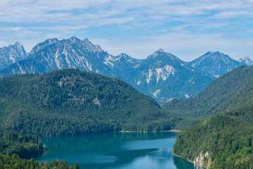 Naklejka na ściany i meble Beautiful summer day in bavarian Alps with a view to Alpsee lake and Neuschwanstein castle Germany from hiking trail 