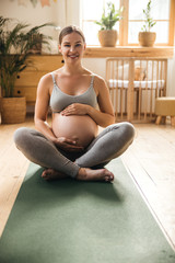 Obraz premium Beautiful pregnant lady holding her belly and smiling