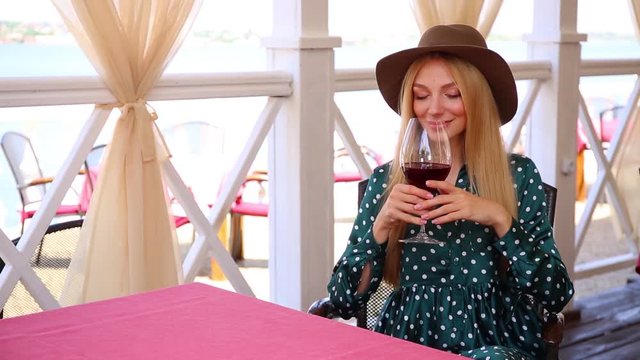 Beautiful young woman drinking wine in outdoor restaurant, space for text