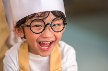 Portrait cute little Asian happy boy interested in cooking with mother funny in home kitchen. People lifestyles and Family. Homemade food and ingredients concept. Baking Christmas cake and cookies