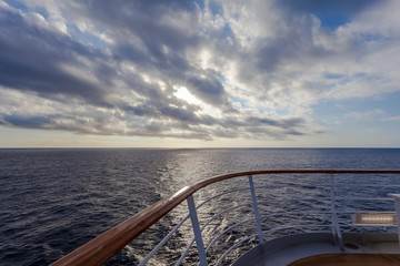 Fototapeta premium Sun filtering through the clouds over the sea seen from the cruise ship deck