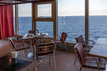 Small tables of the interior bar of a cruise ship with a view of the sea