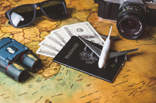 Tourist planning props and travel accessories with American passport, airplane, digital camera, telescope, sunglasses and US dollar banknote money on old grunge style map. Holiday and vacation concept