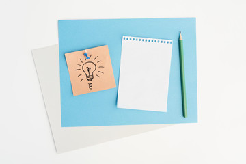 High angle view of drawn light bulb on sticky note attached with pushpin over white background