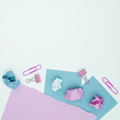 Elevated view of pink and blue card paper and paperclip over white surface
