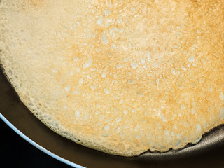 golden thin porous pancake in a pan close-up