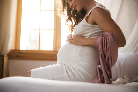 Charming pregnant woman touching her belly and smiling