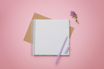Blank notepad, flowers and pen as mockup for your design. Pink background, flat lay style.